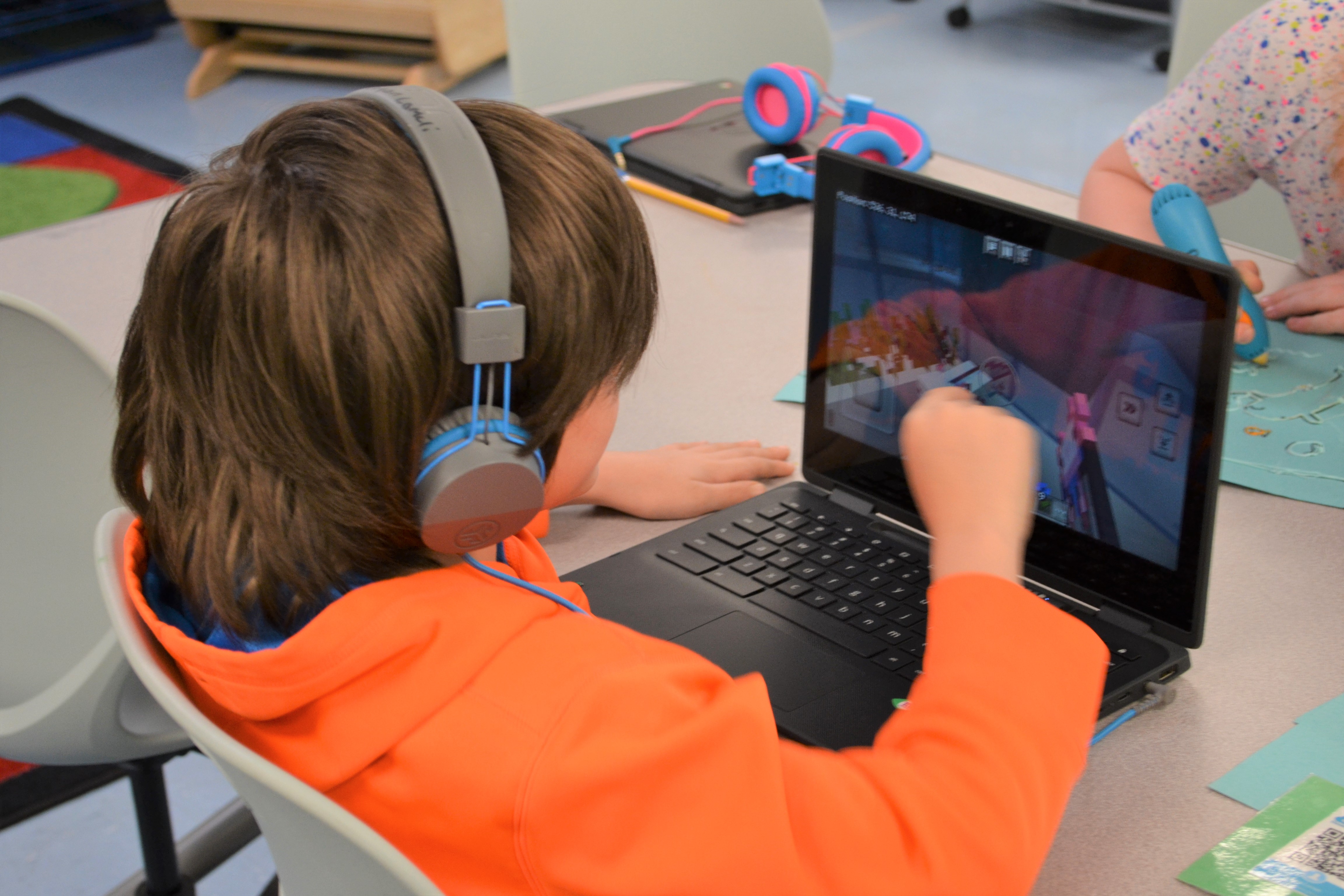 Student engages in a Minecraft challenge for Read across America while another adds texture to art using a 3D pen