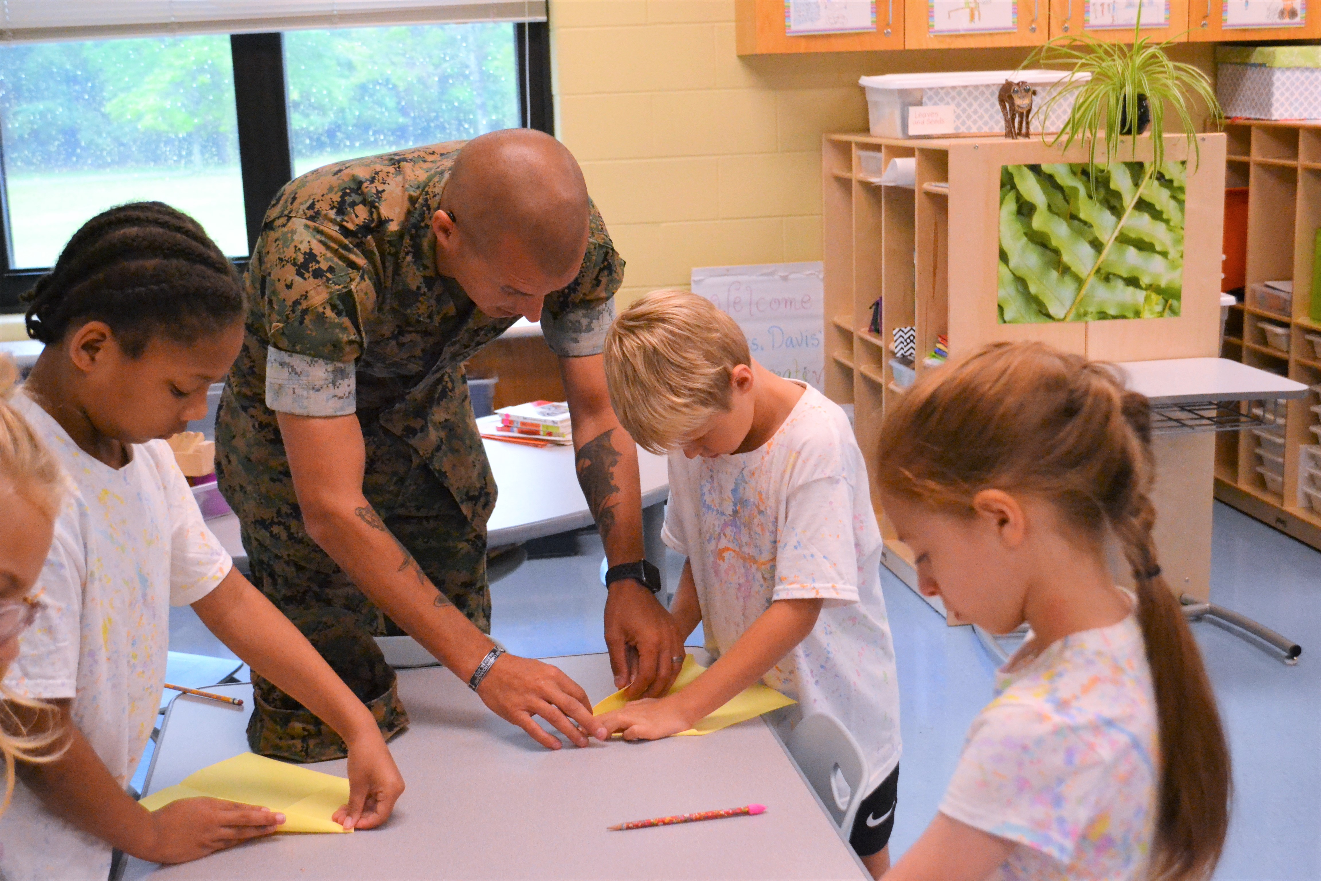 A father helps their child fold a paper air plane