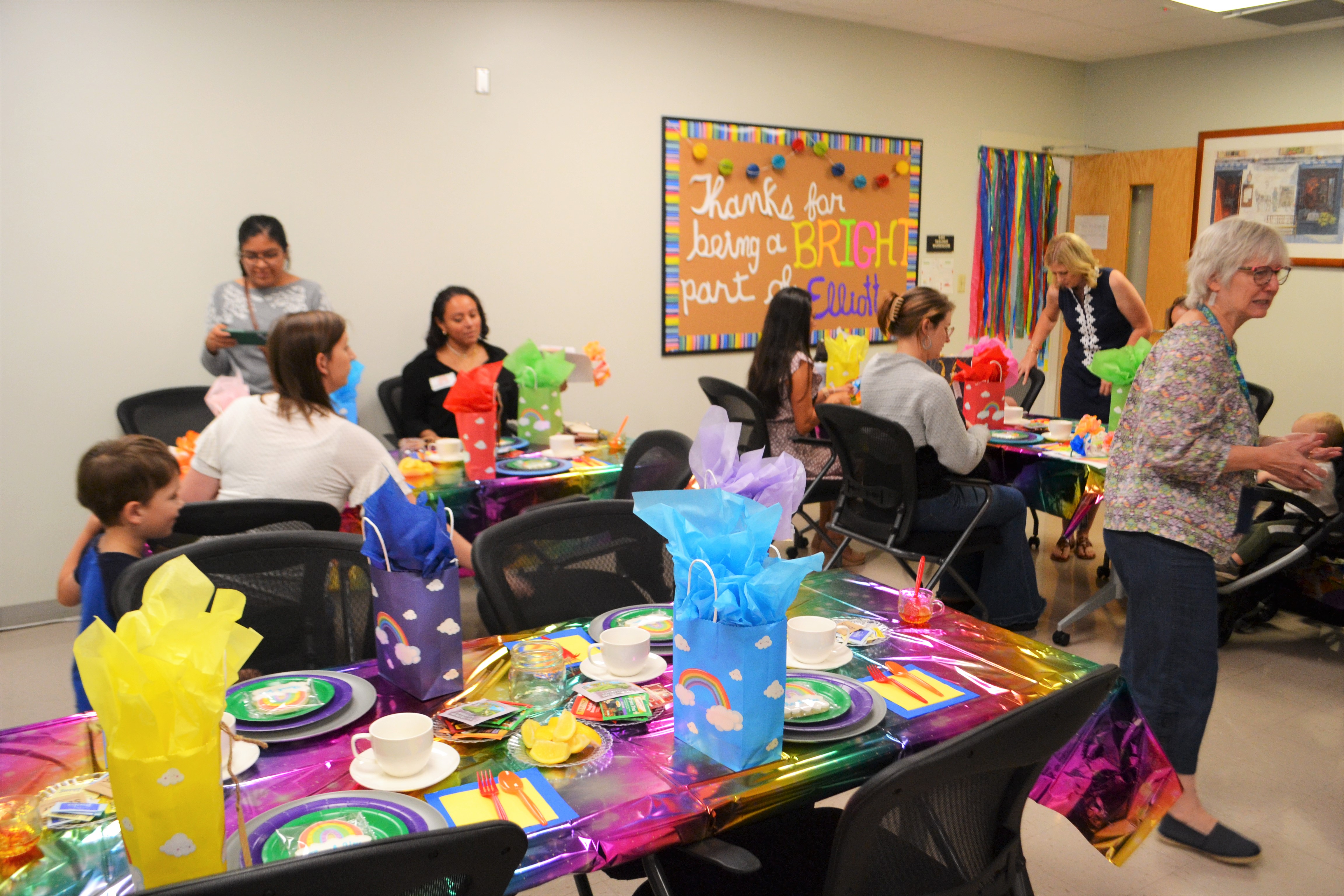 volunteers sit at tables decorated set with bright colors