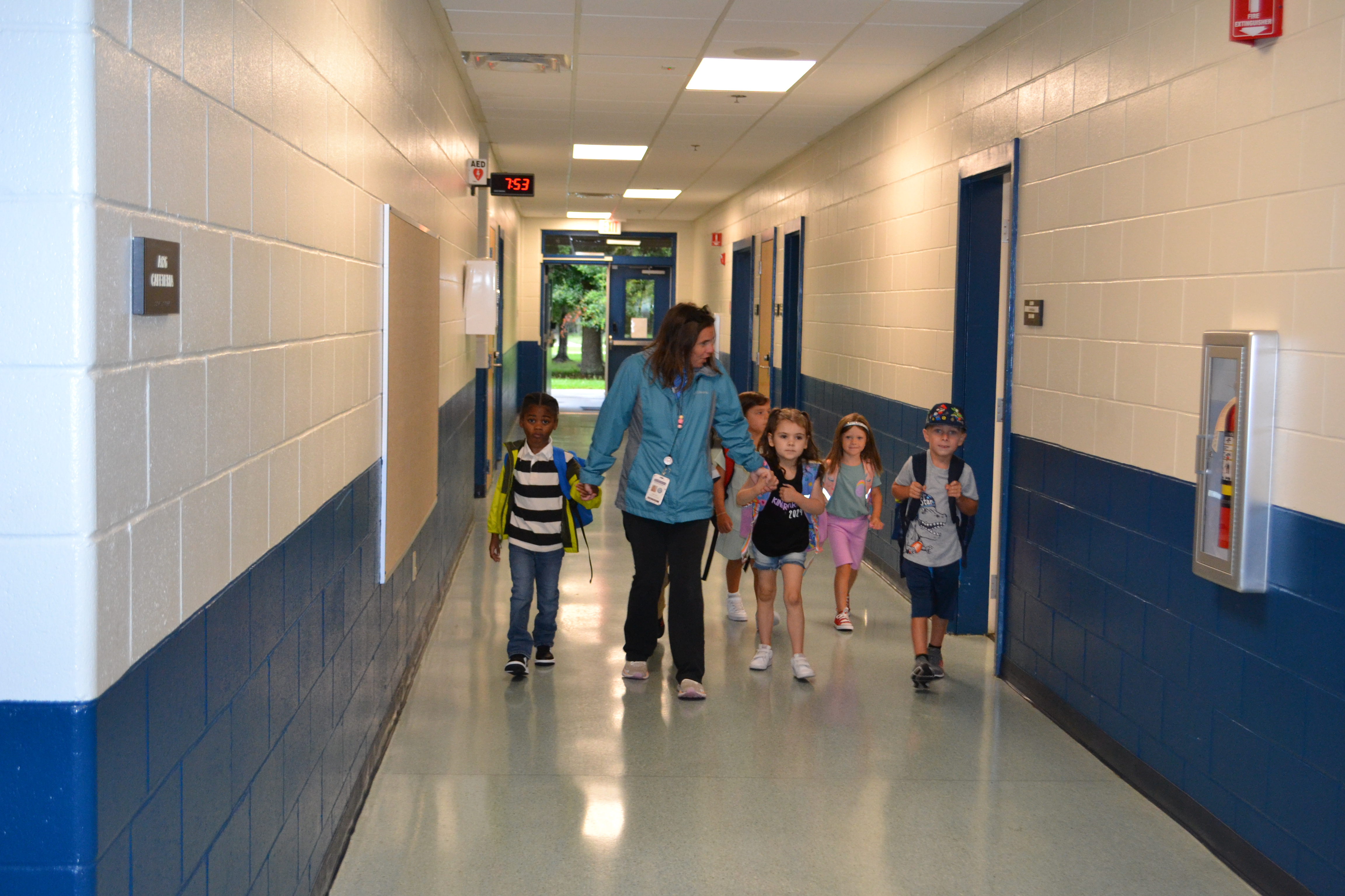 Students walk into the school with a teacher for their first day of school