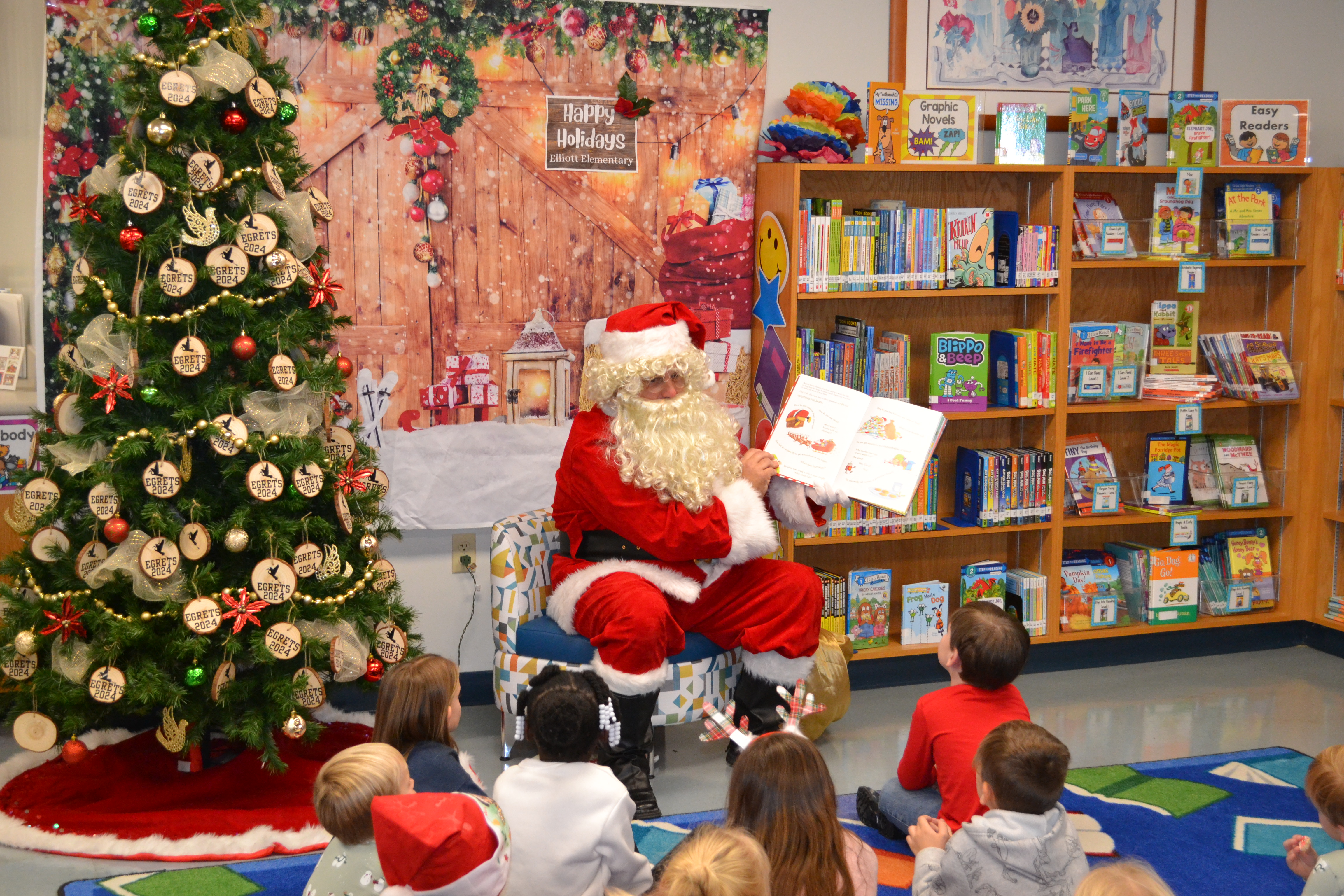 Santa Clause reads a storybook to children sitting on a carpet